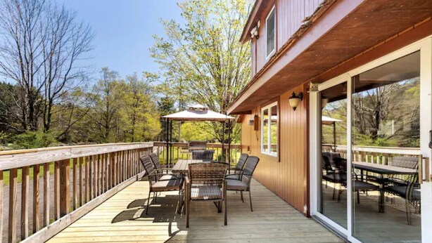 A wooden deck with outdoor furniture and a glass door leading to a covered patio area.