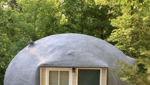 A geodesic dome structure with a small entrance and a window.