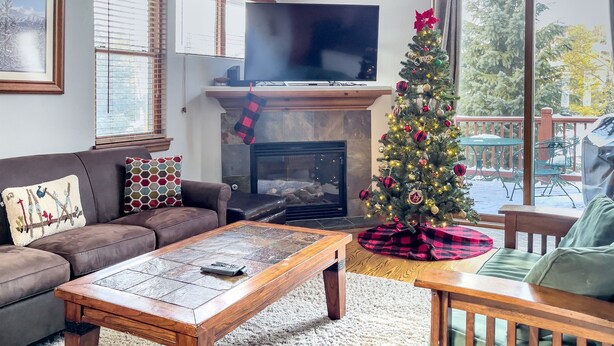 Un accogliente soggiorno con camino, albero di Natale e una grande televisione.
