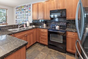 A kitchen with wooden cabinets, a stainless steel refrigerator, a microwave, and a stove. - Beautiful Home with Private Hot Tub Deck Fireplace (Breckenridge)