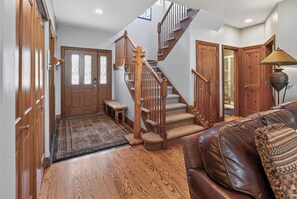 A spacious hallway with a wooden staircase, a bench, and a leather sofa. - Beautiful Home with New Private Hot Tub. Fireplace (Breckenridge)