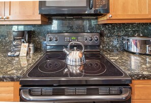 A kitchen with a stove, microwave, and granite countertop.