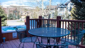 Una terrazza in legno con una vasca idromassaggio, sedie in metallo e un tavolo.