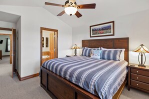A bedroom with a wooden bed, two bedside lamps, a ceiling fan, and a framed picture on the wall. - Beautiful Home with New Private Hot Tub. Fireplace (Breckenridge)