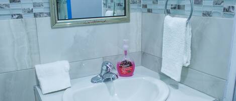 A bathroom with a white sink, a mirror, and a hand soap dispenser.