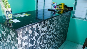 A reception desk with a mosaic tile pattern, a glass top, and various items on the counter. - Ocean View Beach Hotel (Ocho Rios)