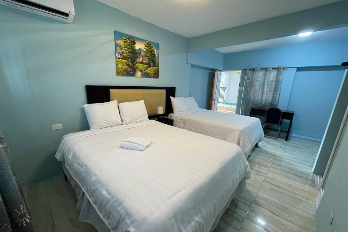 Ein Hotelzimmer mit zwei Betten, einem Gemälde an der Wand und Blick ins Freie.