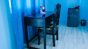 A room with a dining table and chairs, a refrigerator, and a trash bin. - Ocean View Beach Hotel (Ocho Rios)