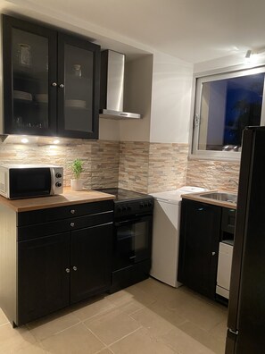A modern kitchen with dark cabinets, a microwave, stove, oven, and a window with a view.