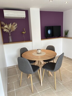 A dining area with a round wooden table, six grey upholstered chairs, and a central decorative bowl.
