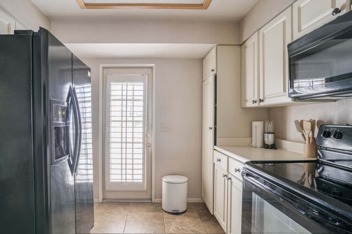 Una cocina equipada con refrigerador, horno, microondas y alacenas.