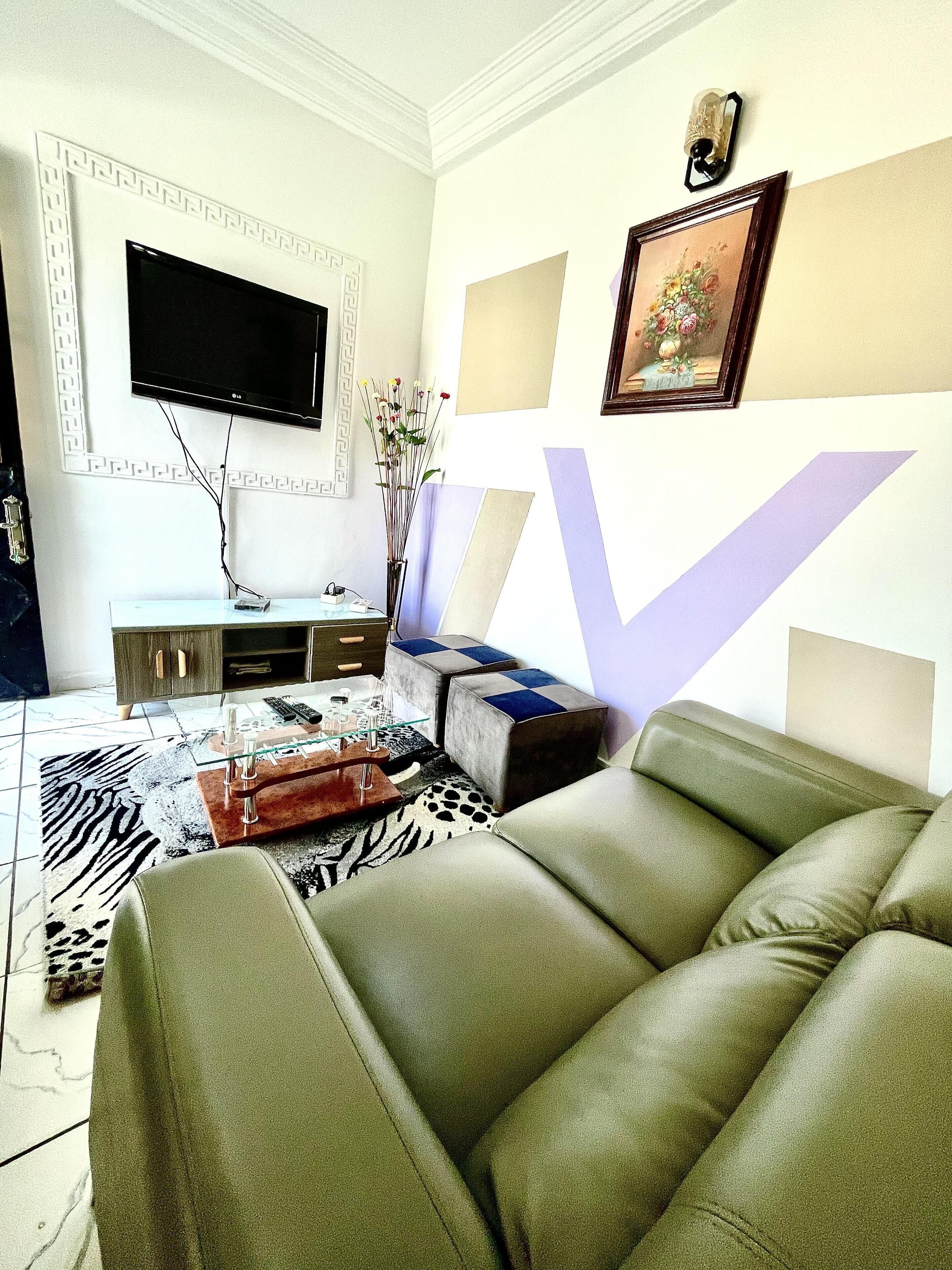 Una sala de estar con un sofá, una mesa de centro, un televisor y un jarrón decorativo.