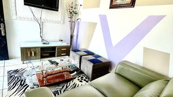Una sala de estar con un sofá, una mesa de centro, un televisor y un jarrón decorativo.