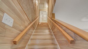 Una escalera de madera con barandas blancas y un interruptor de luz en la pared.