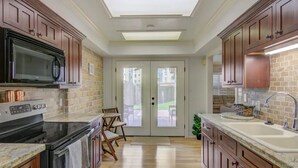 Una cocina con armarios de madera, un microondas negro, una estufa y un lavamanos.