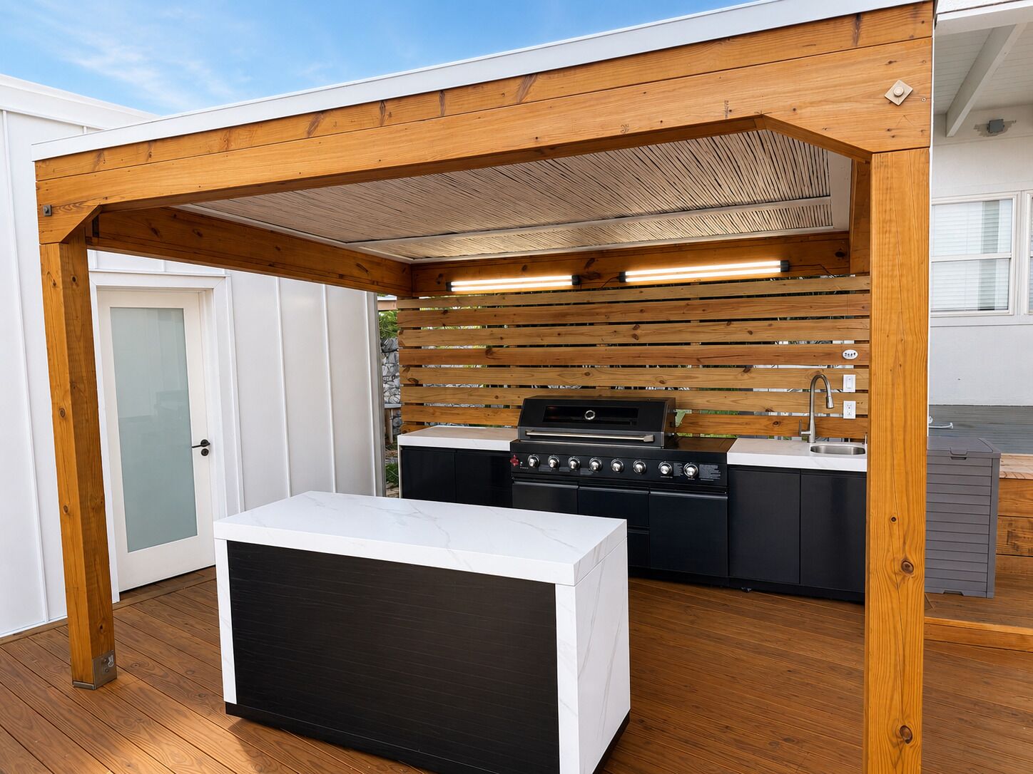 Una cocina exterior moderna con una parrilla integrada, un lavamanos y una encimera.