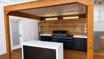 Una cocina exterior moderna con una parrilla integrada, un lavamanos y una encimera.