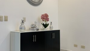 Un intérieur moderne avec un mur blanc, un meuble noir et blanc, une grande horloge murale et un sol en marbre.