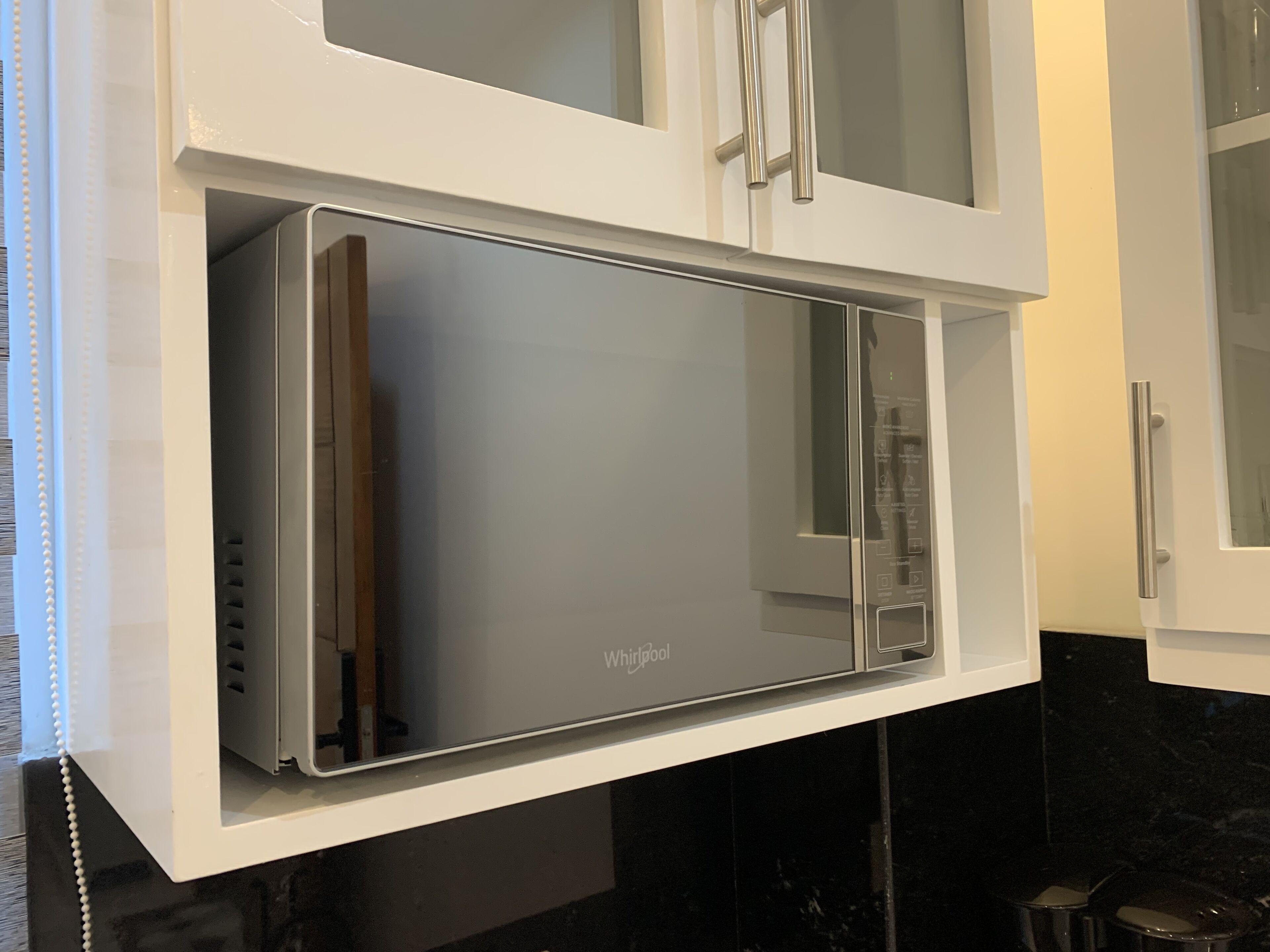 A kitchen with a built-in microwave and white cabinets.