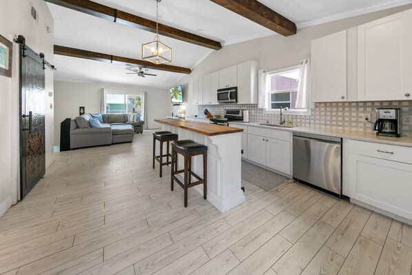 A modern kitchen with white cabinets, a wooden island, and a built-in oven. - Beach Side Destin Retreat (Destin)