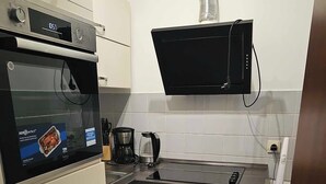 Een compacte keuken met een inbouwoven, een magnetron en een koffiezetapparaat.