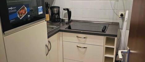 A compact kitchen with a built-in oven, a microwave, and a coffee maker.