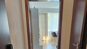 Een gang met houten vloer die leidt naar een eetgedeelte met een tafel en stoelen.