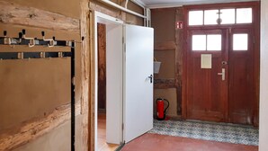 A room with a wooden door, a white wall, and a tiled floor.