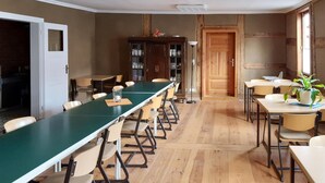 A conference room with a long table and chairs, wooden floors, and a cabinet with dishes.