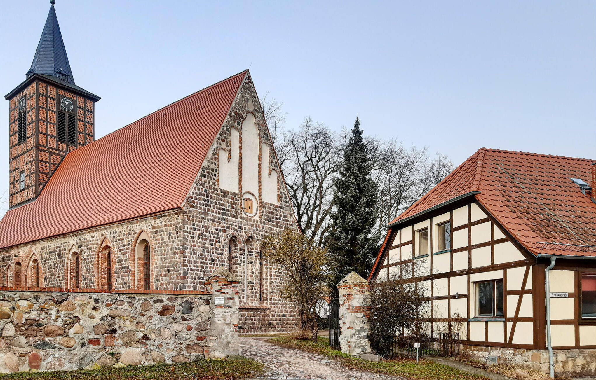 Una chiesa storica con un campanile imponente e una tradizionale casa a graticcio adiacente.
