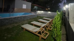 Ein Poolbereich mit Liegestühlen und einer Steinmauer.