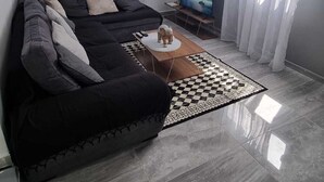 Ein modernes Wohnzimmer mit einem schwarzen Sofa, einem Couchtisch und einem Flachbildfernseher.