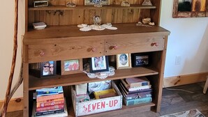 A wooden bookshelf with framed photos and books, a decorative plate, and a painting above it. - Cozy new built home for 2, country living with city near by (West Olive)