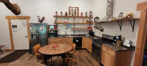 A compact kitchen with a refrigerator, microwave, stove, and wooden cabinets. - Cozy new built home for 2, country living with city near by (West Olive)