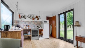 A modern kitchen with a wooden countertop, a built-in oven, a microwave, and hanging pots.