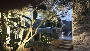 Un mur de pierre, une terrasse en bois et un chemin menant à un bâtiment.