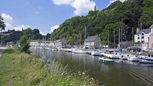 Un port de plaisance où des bateaux sont amarrés le long d’une rive, entouré de bâtiments et d’une végétation luxuriante.
