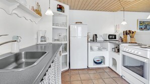 Eine kleine Küche mit Spüle, Kaffeemaschine, Kühlschrank, Mikrowelle und Herd.