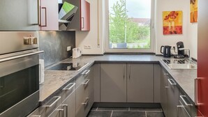 Et moderne køkken med indbygget ovn, mikroovn og kaffemaskine.