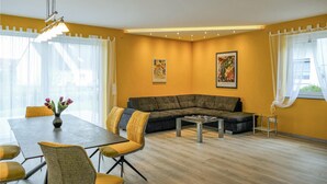 En moderne stue med en hjørnesofa, et spisebord med stole og billedkunst på væggene.