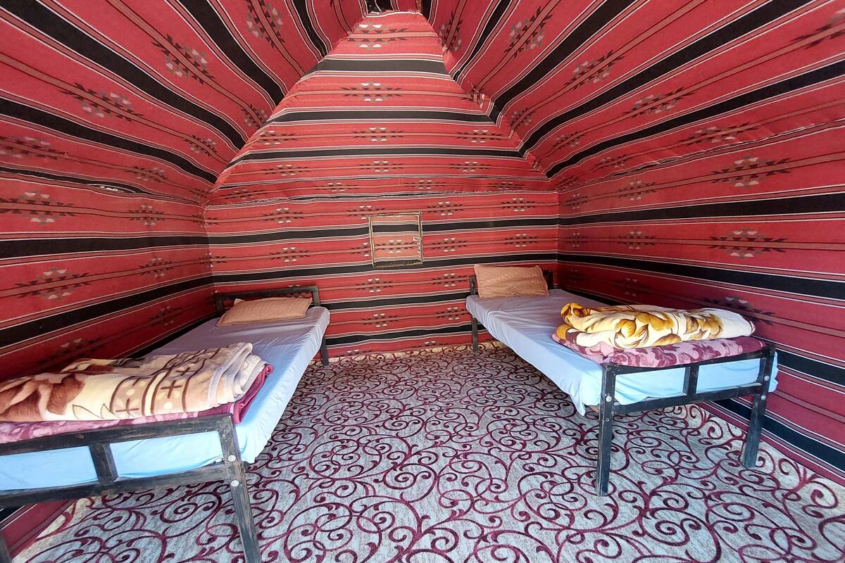 A room with two beds, each with a different patterned bedspread. The walls are adorned with a red and black striped design.