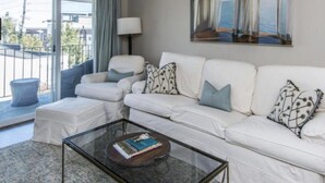 A modern living room with a white sofa set, a glass coffee table, and a painting of sailboats. - Downtown Charleston! Walking distance to The Battery! (Charleston)