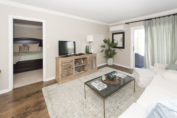 A modern living room with a sofa, coffee table, TV, and a plant. - Downtown Charleston! Walking distance to The Battery! (Charleston)