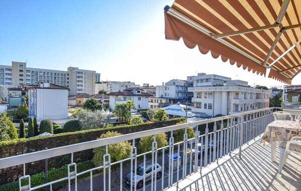 Un balcon doté d’une rambarde en métal, donnant sur un parking et des immeubles.