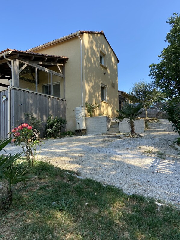 Une maison à deux étages, avec une façade de couleur beige, une clôture en bois et une allée gravillonnée.