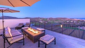 Eine Terrasse mit Feuerstelle, Sitzgelegenheiten und Blick auf die Landschaft.