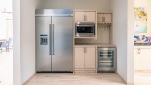 Eine kompakte Küche mit einem Edelstahlkühlschrank, einer Mikrowelle und einem eingebauten Backofen.