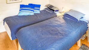 A bed with a blue patterned bedspread and pillows, a bedside lamp, and a framed picture on the wall.