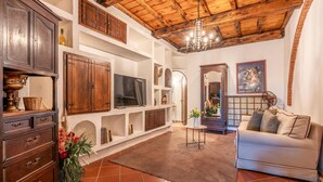 Una sala de estar con techo de madera, televisor, sofá y chimenea.
