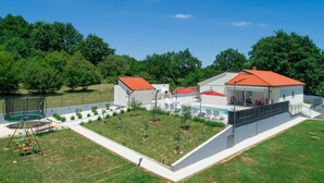 Una casa moderna con piscina, un patio cubierto y un jardín cercado.